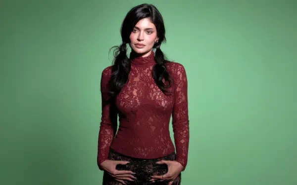 4K Ultra HD PC desktop wallpaper: portrait of a woman in a burgundy lace turtleneck, hands on hips, posed against a solid green background.
