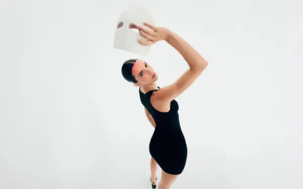 Celebrity model in a black dress striking a graceful, high-fashion pose against a minimalist white backdrop — 4K Ultra HD PC desktop wallpaper.