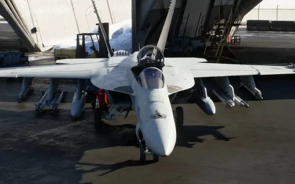 HD PC desktop wallpaper of an Ace Combat 8: Wings of Theve jet fighter, a white military aircraft parked head-on by a hangar with missiles mounted under its wings.