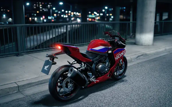 Red Honda CBR500R Four sportbike parked on a city street at night, featured in a 5K Ultra HD desktop wallpaper background.