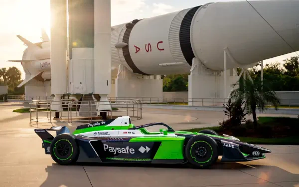 Envision Racing Formula E race car beneath a rocket at sunset, 8K Ultra HD PC desktop wallpaper and background.