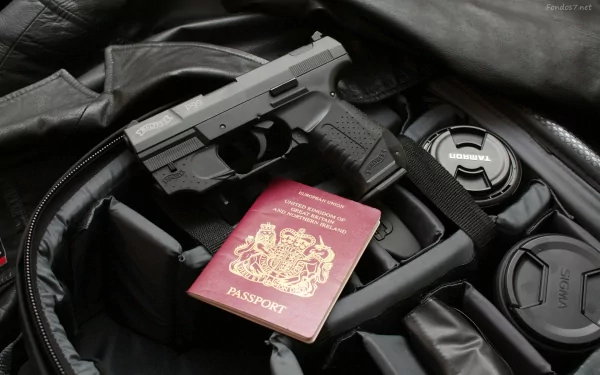 HD desktop wallpaper featuring a Walther P99 pistol resting on a black bag alongside a British passport and a camera lens cap.