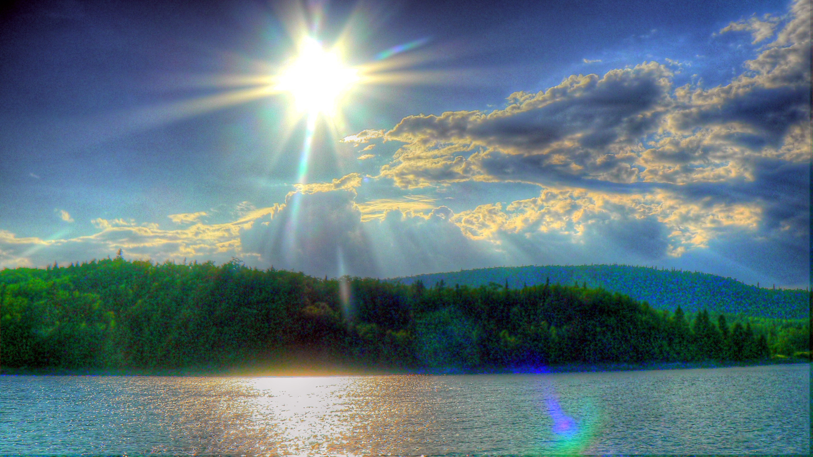 The stunning HDR photo showcases a majestic sky reflecting off a calm lake, with the vibrant sun shining brightly.