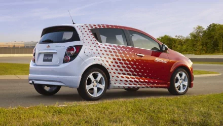 HD PC desktop wallpaper and background: Chevrolet Sonic vehicle in red-and-white dotted livery parked beside a road, with grassy foreground and a clear sky.