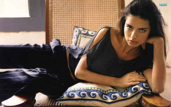 HD PC desktop wallpaper featuring celebrity Adriana Lima reclining on patterned cushions with a relaxed yet intense expression.