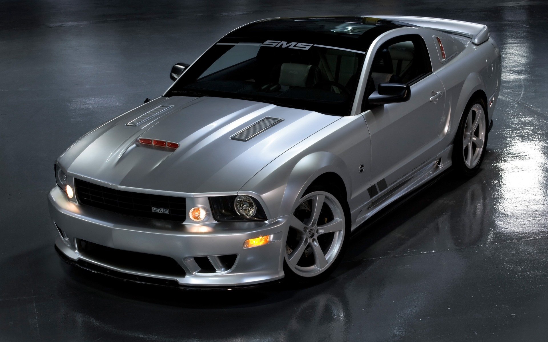 HD desktop wallpaper of a sleek silver Ford Mustang parked on a glossy floor, showcasing its sporty design and aggressive front grille.