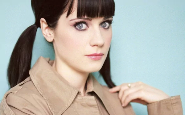 HD desktop wallpaper featuring Zooey Deschanel, showcasing her distinctive style with bangs and pigtails against a soft blue backdrop.