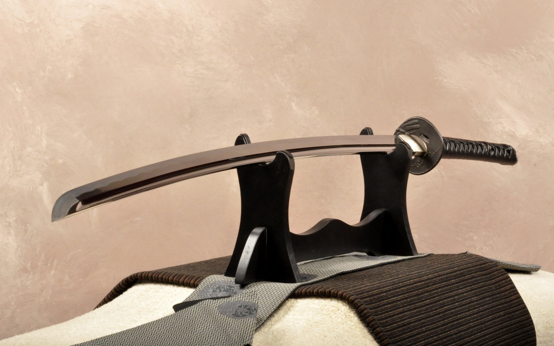 A sleek, man-made sword rests elegantly on a display stand, showcasing its polished blade and intricate handle against a soft, muted background. An eye-catching HD desktop wallpaper.