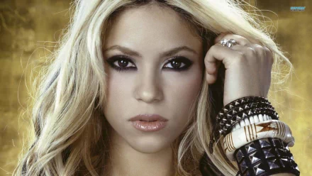 A close-up HD wallpaper of Shakira with intense eyes, blonde hair, and stylish bracelets against a rich background, tagged with music.