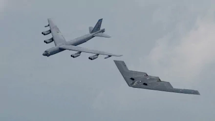 A striking HD wallpaper featuring a stealth aircraft flying alongside a military bomber against a cloudy sky, showcasing cutting-edge aviation technology.