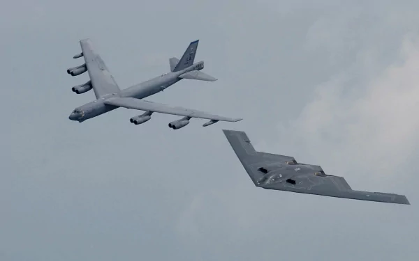 A striking HD wallpaper featuring a stealth aircraft flying alongside a military bomber against a cloudy sky, showcasing cutting-edge aviation technology.
