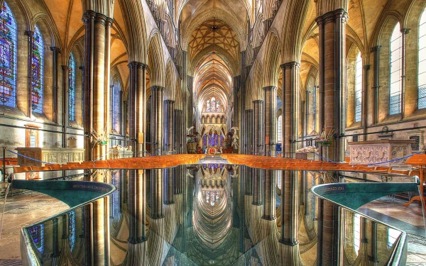 Salisbury Cathedral interior: vaulted arches, stained glass and silver-toned reflective pool mirroring the nave and columns — HD PC desktop wallpaper/background.