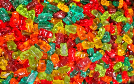 HD wallpaper showcasing a colorful assortment of gummy bears in various shades of red, green, yellow, and orange, creating a vibrant and playful background for any desktop.
