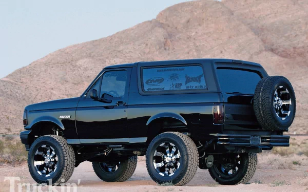 HD PC desktop wallpaper/background: a lifted black Ford Bronco vehicle parked on desert terrain with rocky hills in the background.