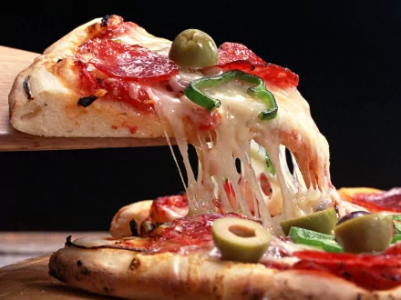 A delicious slice of pizza topped with pepperoni, olives, and green peppers, melting cheese pulling away, set against a dark background—an enticing HD desktop wallpaper.