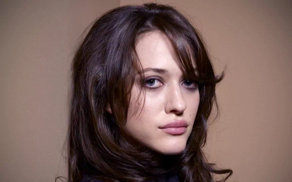HD PC desktop wallpaper featuring a close-up portrait of celebrity Kat Dennings with dark hair and a neutral expression against a plain background.