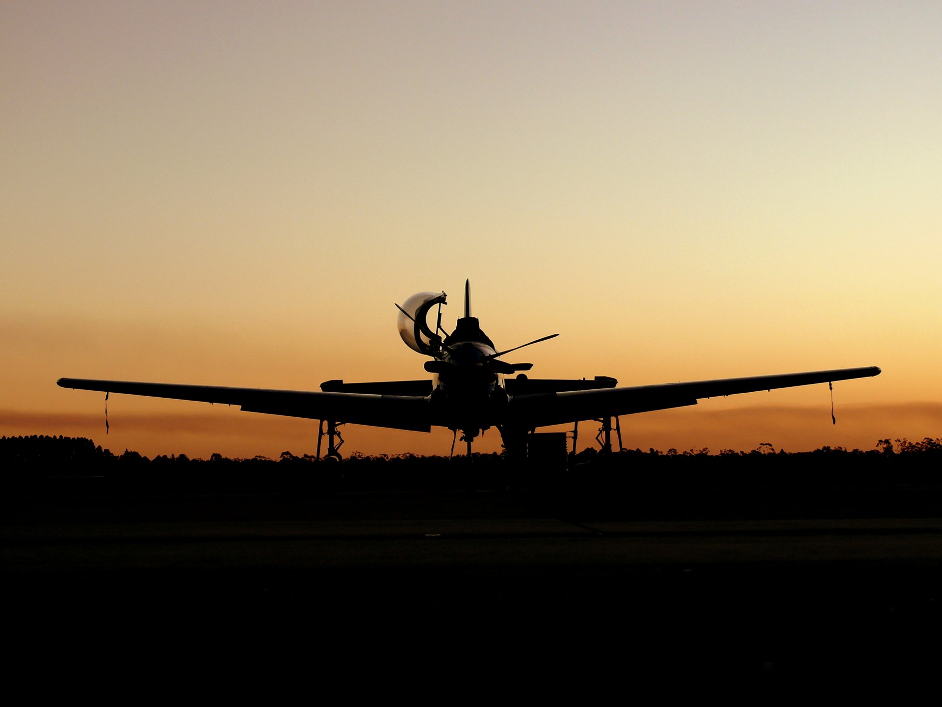 A silhouette of a military aircraft against a stunning sunset, creating a striking HD desktop wallpaper and background. The scene captures the essence of aviation and adventure.