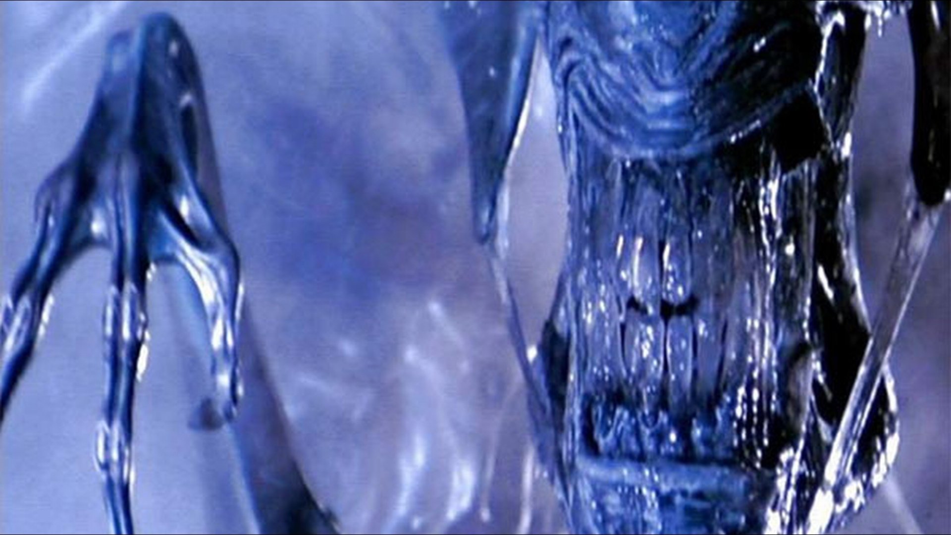 HD PC desktop wallpaper showing a close-up of a menacing movie alien with a glossy biomechanical exoskeleton, exposed teeth and elongated skull in misty blue light.
