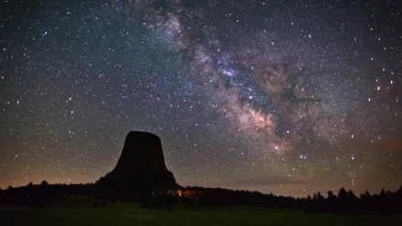 A stunning HD wallpaper featuring the Milky Way stretching across the night sky above a prominent rock formation, capturing the beauty of the cosmos in a sci-fi aesthetic.