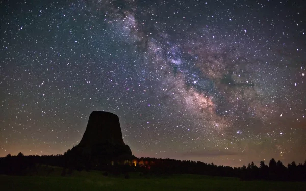 A stunning HD wallpaper featuring the Milky Way stretching across the night sky above a prominent rock formation, capturing the beauty of the cosmos in a sci-fi aesthetic.