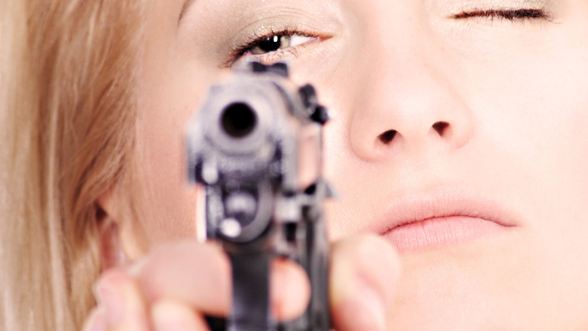 Close-up HD PC desktop wallpaper of a woman aiming a handgun, featuring a Girls & Guns theme with a focused expression.