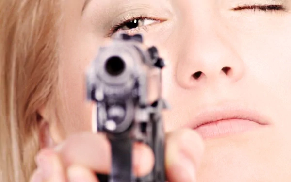 Close-up HD PC desktop wallpaper of a woman aiming a handgun, featuring a Girls & Guns theme with a focused expression.