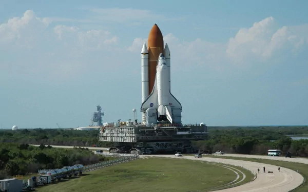 HD desktop wallpaper featuring the Space Shuttle Discovery on a vehicle, set against a clear sky and green landscape background.
