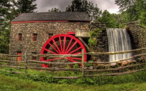 4K Ultra HD wallpaper of a man-made stone watermill with a vibrant red water wheel, next to a small cascading waterfall surrounded by greenery.