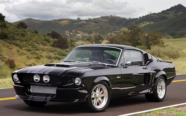 A sleek black Shelby GT500 Classic Recreation muscle car, showcased on a scenic road with mountains in the background, captured in stunning 4K Ultra HD detail.