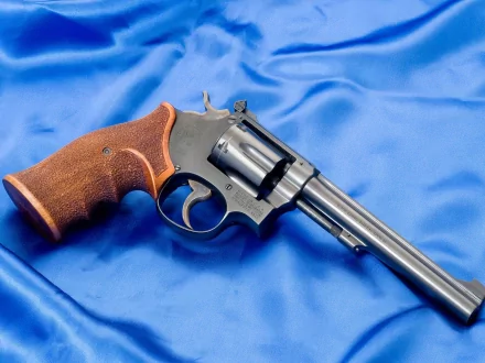 HD PC desktop wallpaper: man-made Smith & Wesson revolver with wooden grip resting on blue satin background.