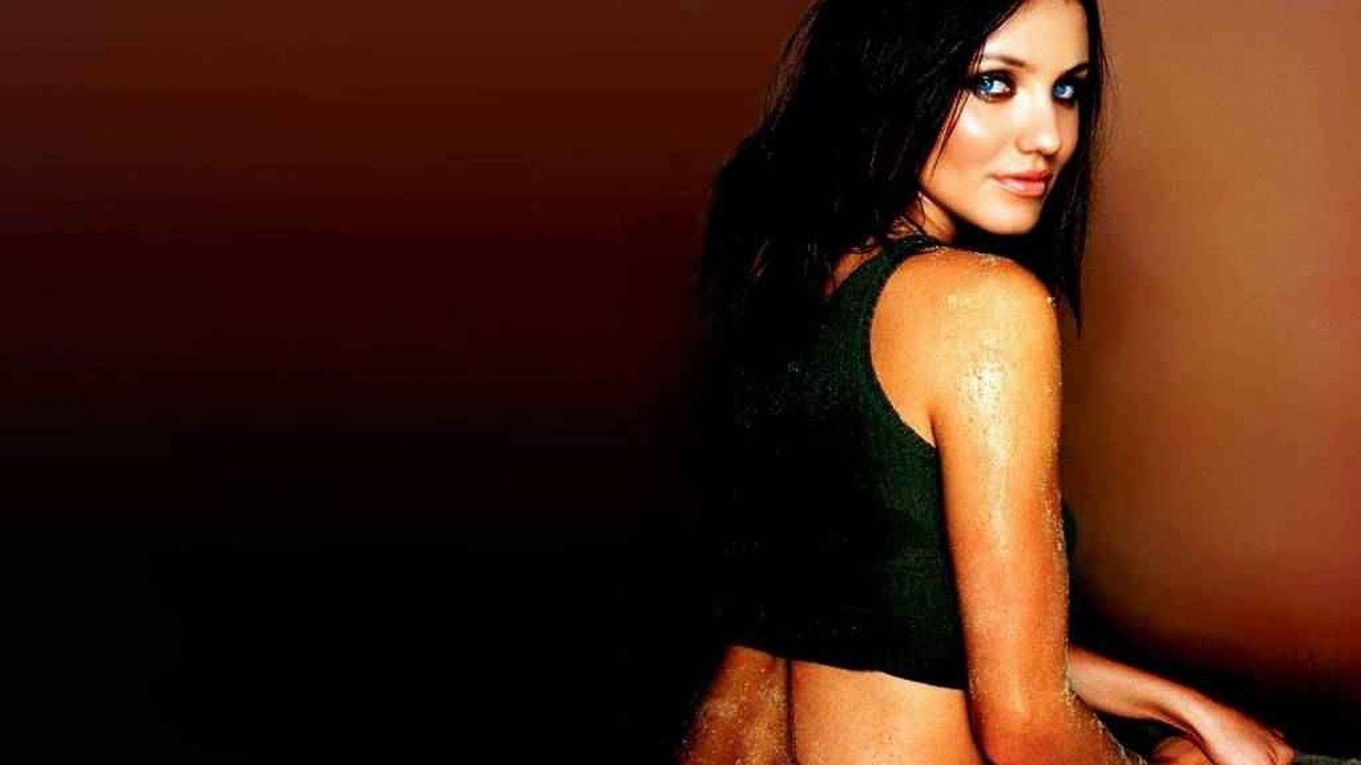 HD desktop wallpaper featuring a celebrity woman with long dark hair and a black top against a dark brown background.