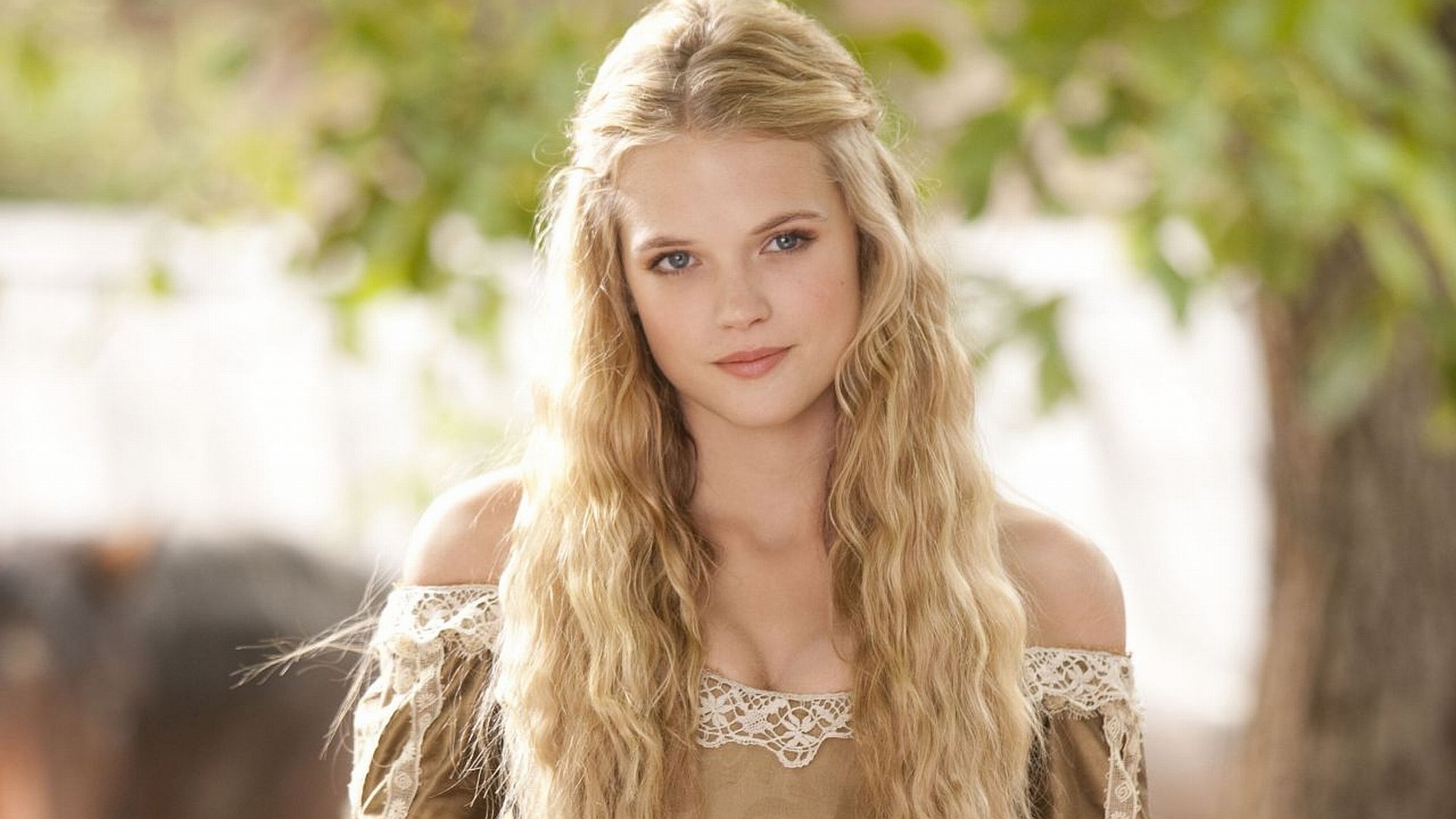 HD PC desktop wallpaper of a long-haired woman in a lace-trimmed period dress, outdoors in soft light, a still from the movie The Three Musketeers.