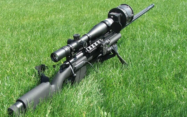 A close-up of a sniper rifle resting on vibrant green grass, showcasing the intricate details of its design. This HD image serves as a striking desktop wallpaper and background.