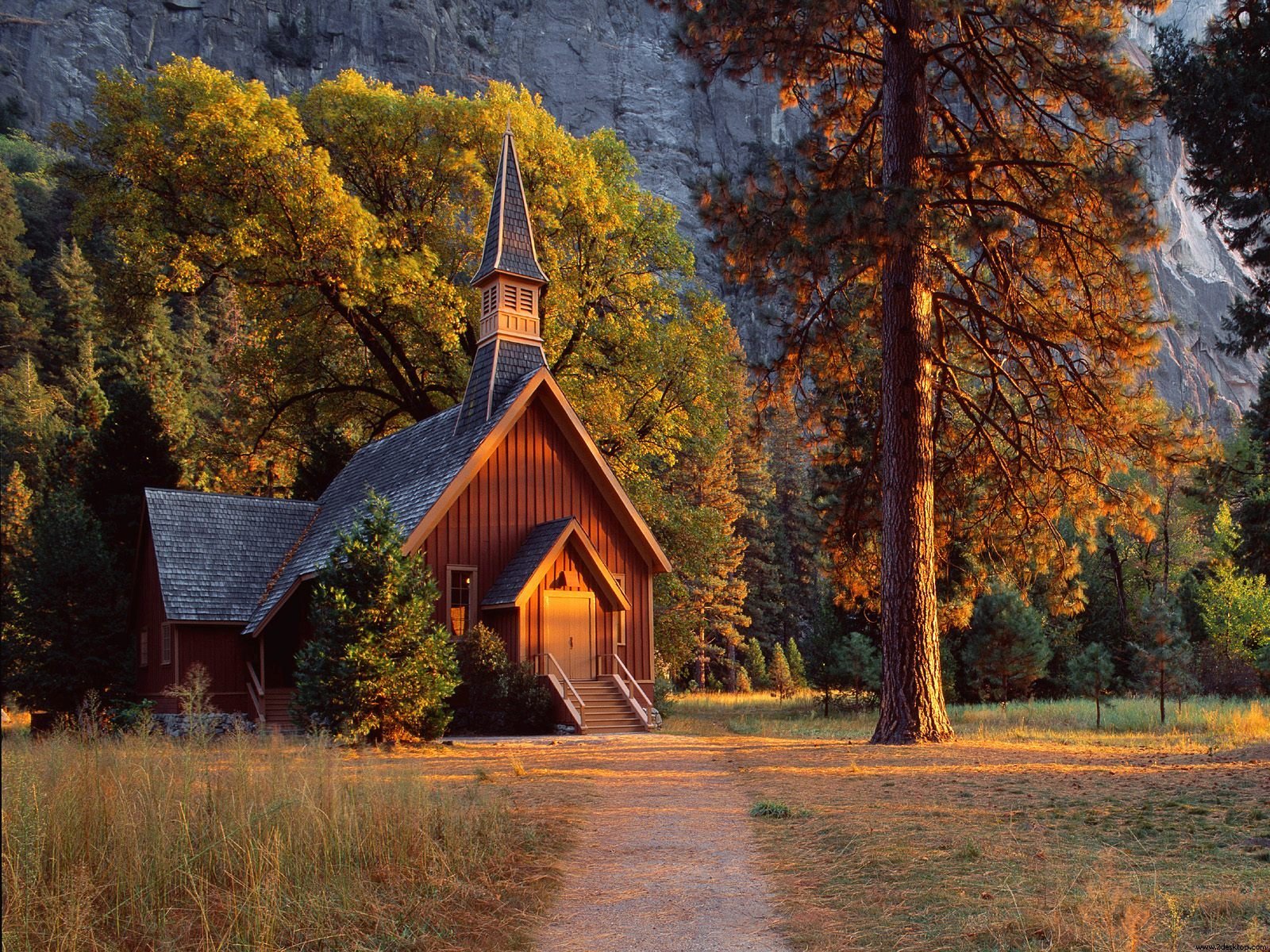 HD desktop wallpaper of a charming wooden church surrounded by autumn trees, showcasing serene religious architecture nestled in a peaceful natural setting.