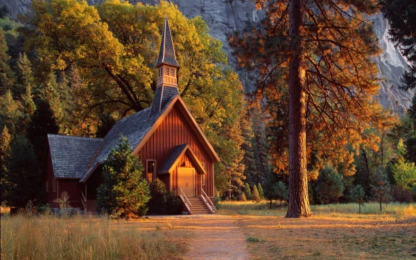 HD desktop wallpaper of a charming wooden church surrounded by autumn trees, showcasing serene religious architecture nestled in a peaceful natural setting.
