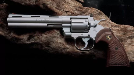 HD PC desktop wallpaper of a man-made Colt Python revolver with wooden grips resting on rugged bark, close-up detail.