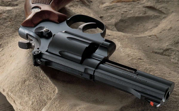 HD desktop wallpaper featuring a close-up of a man-made Smith & Wesson revolver resting on a textured stone surface.