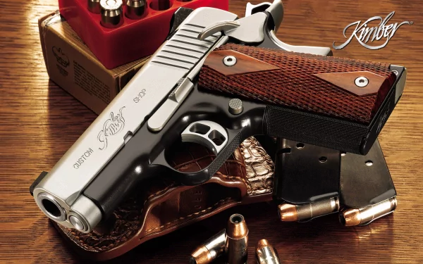 A close-up of a Kimber pistol on a wooden surface, showcasing its sleek design alongside ammunition and a magazine, set against a backdrop emphasizing its man-made craftsmanship.