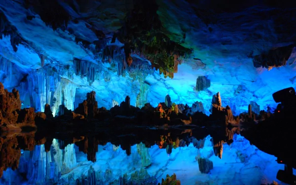 HD PC desktop wallpaper showcasing the stunning natural beauty of Reed Flute Cave with vibrant blue lighting highlighting limestone formations and their reflections in water.