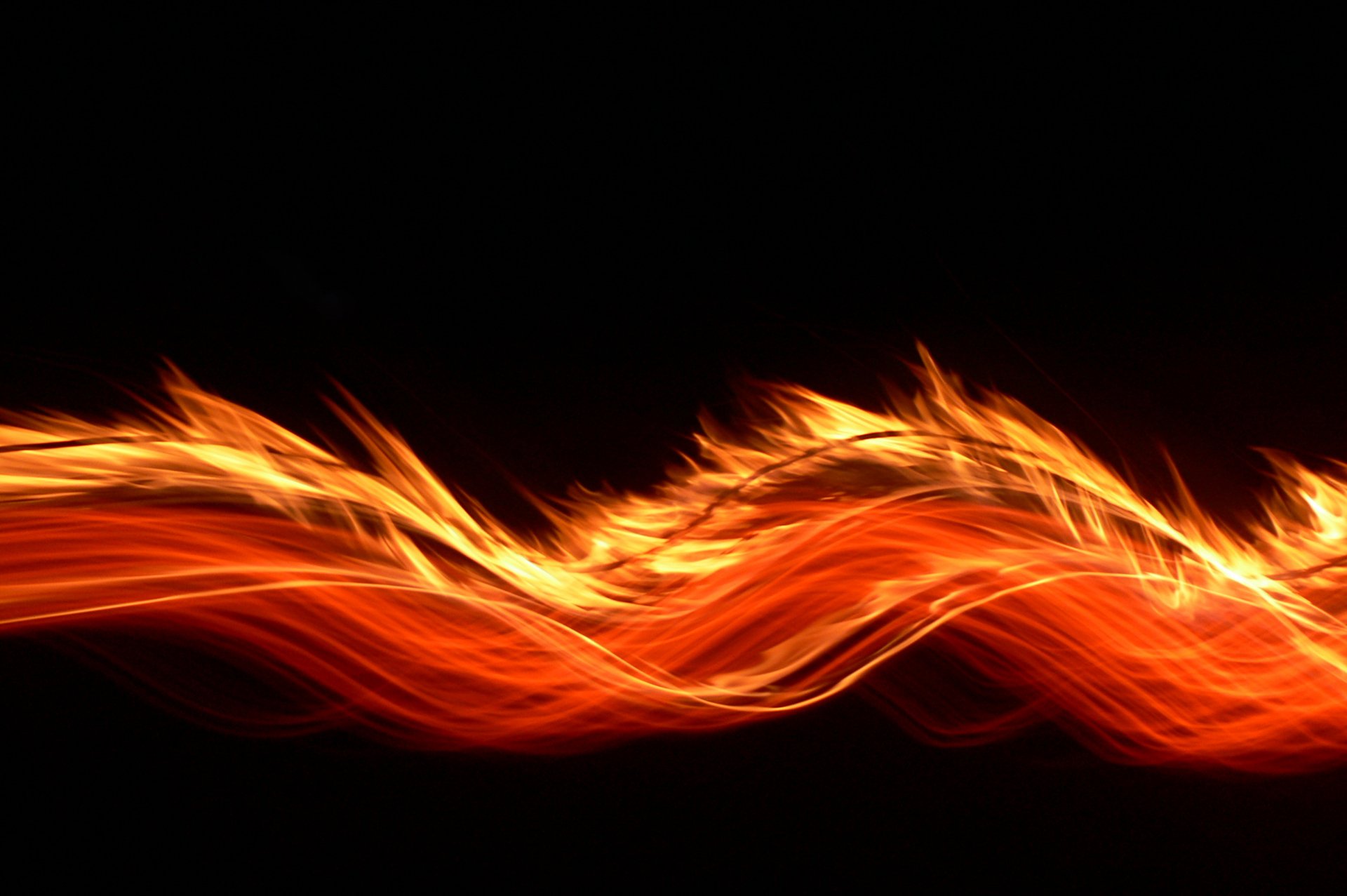 A vibrant, abstract display of swirling flames contrasts against a black background, creating a striking artistic wallpaper for HD PC desktops.