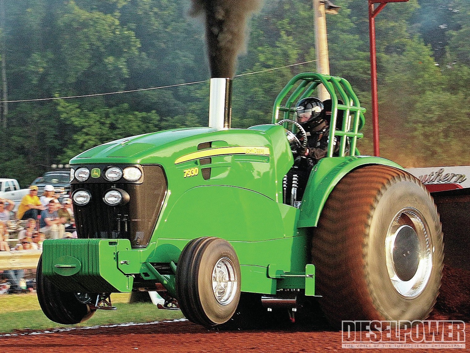 HD desktop wallpaper featuring a green John Deere vehicle, showcasing a powerful tractor in action with large rear tires and a driver inside.
