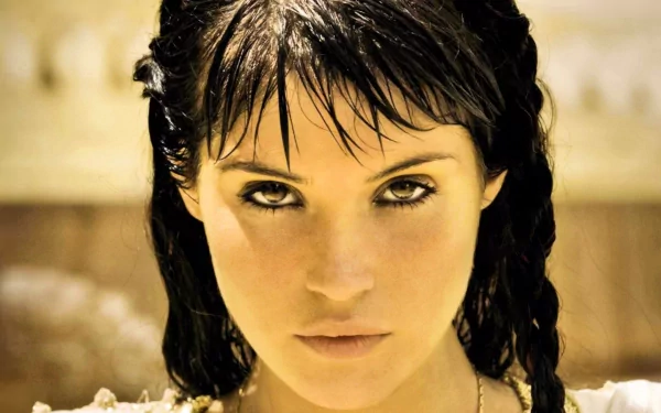 A striking HD wallpaper featuring Gemma Arterton, showcasing her intense expression and captivating gaze, set against a warm background.