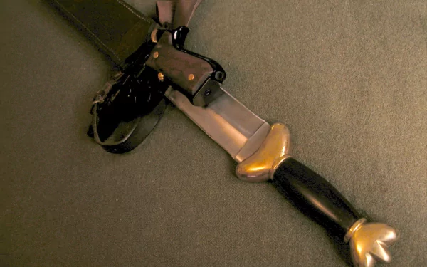 A HD desktop wallpaper featuring a man-made knife with a decorative hilt placed on a surface, accompanied by a pistol and its holster.