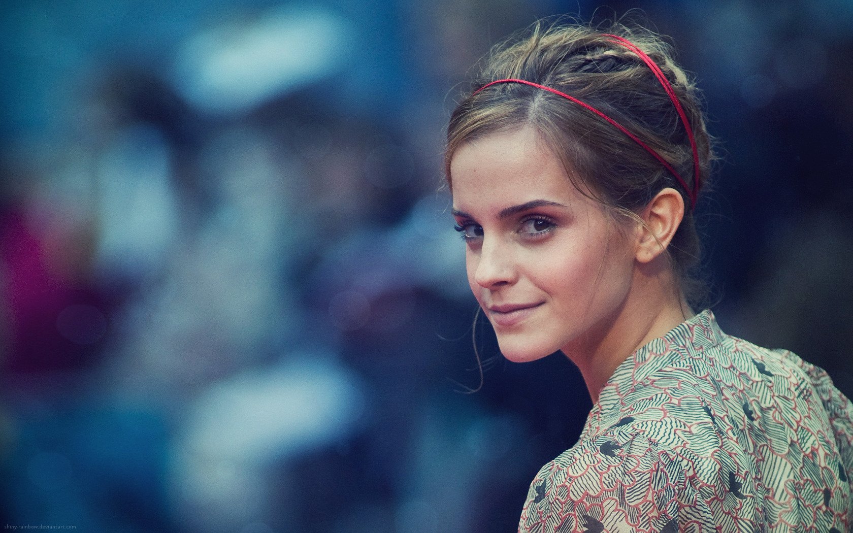 Emma Watson gazes confidently over her shoulder in this stunning HD desktop wallpaper, capturing her charm and poise amidst a vibrant, blurred background.