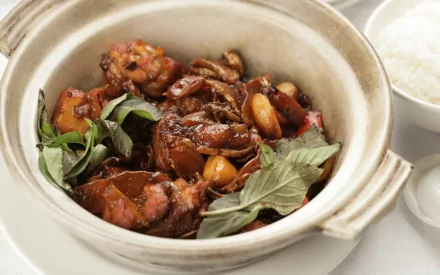 HD desktop wallpaper featuring a close-up of flavorful Chinese food in a clay pot, accompanied by fresh herbs and a bowl of white rice.