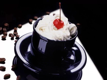 A rich cream-topped drink garnished with a bright red cherry in a black cup and saucer, surrounded by coffee beans, presented as an HD PC desktop wallpaper.