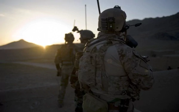 HD desktop wallpaper showing U.S. Army Infantry soldiers equipped for war, advancing through a rugged military terrain at dusk.