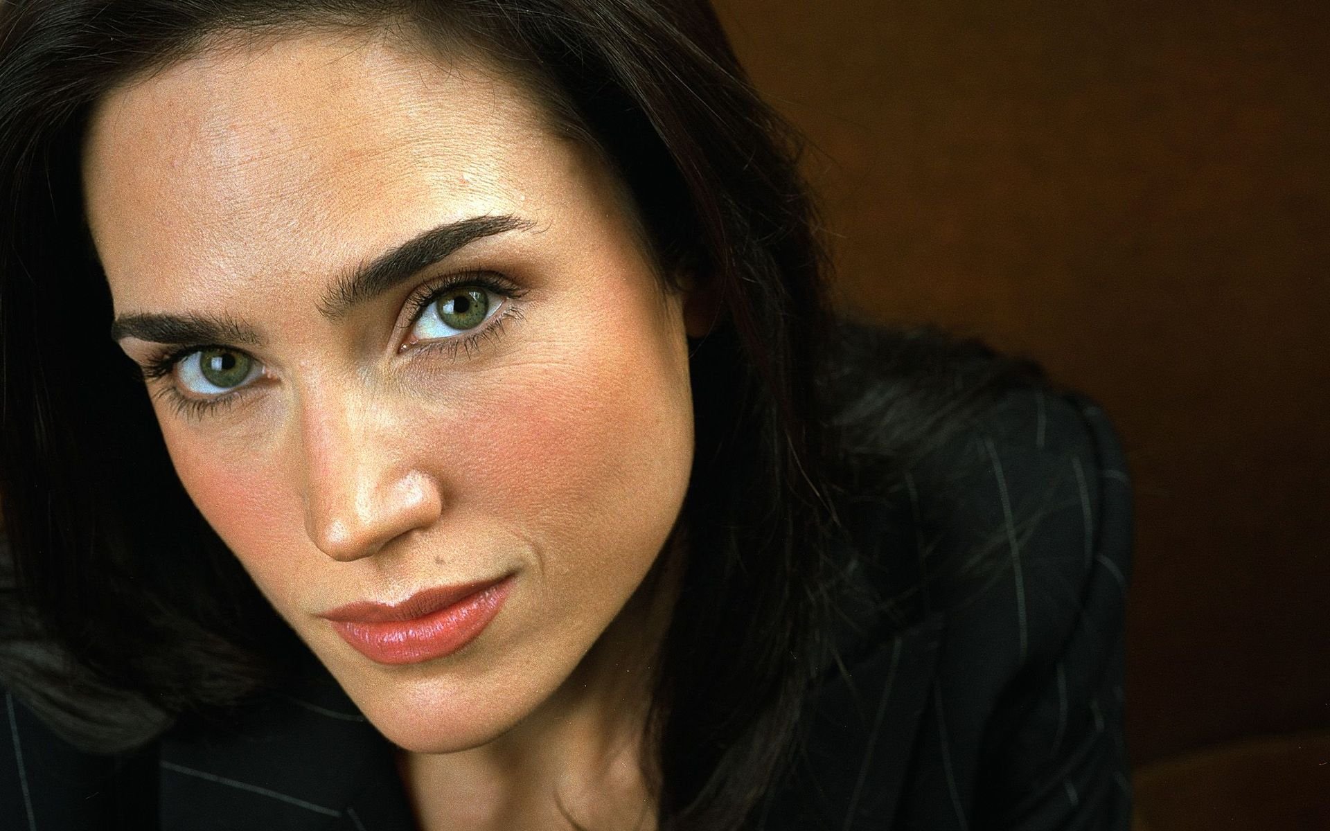 A striking HD wallpaper featuring Jennifer Connelly, showcasing her captivating gaze and elegant style in a dark, classic setting.