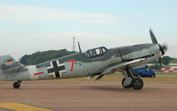 HD desktop wallpaper showcasing a Messerschmitt Bf 109 military aircraft taxiing on a runway under clear skies.