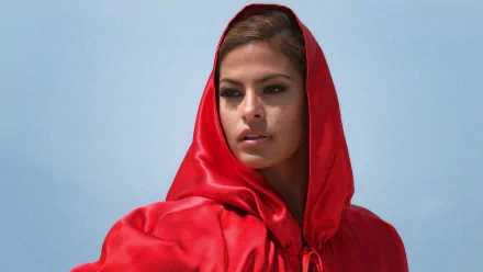 HD desktop wallpaper featuring celebrity Eva Mendes wearing a vibrant red hooded garment against a clear blue sky background.